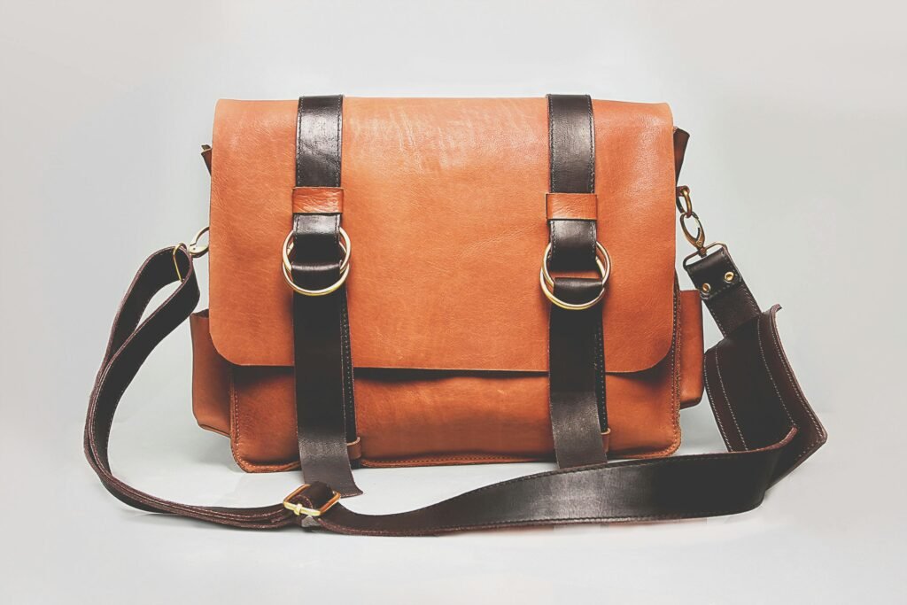 Elegant brown leather briefcase with dark straps and metal buckles, ideal for fashion and business.